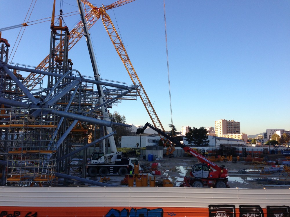 La grue Sarens blanche qui positionne semble t'il la dernière palée de cette rangée de la 3ème station de montage.