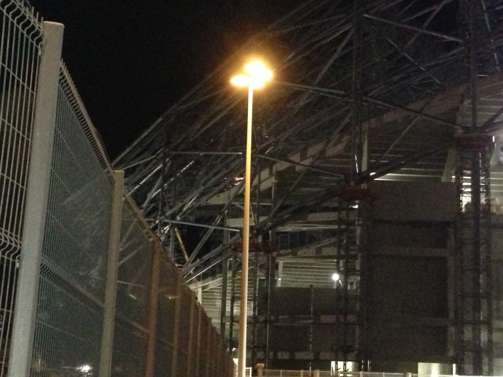 Sur la gauche du pilonne au niveau de la nouvelle tribune on distingue les étincelles du meulage.